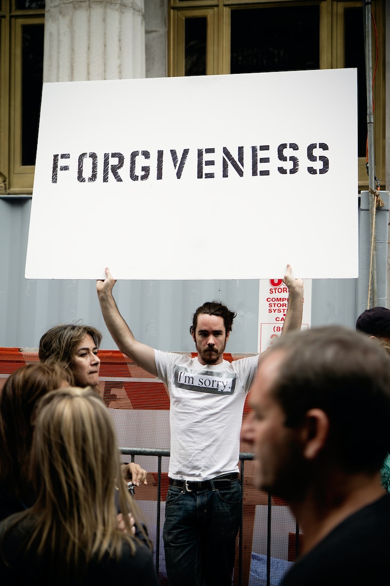 Photo by Felix Koutchinski person holding Forgiveness poster
